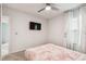Modern bedroom with a mounted TV, soft carpet, and bright window dressed with sheer curtains at 6684 Devlin Ln, Wesley Chapel, FL 33545