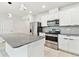 Modern kitchen showcasing stainless appliances, white cabinetry, and a gray granite island and countertops at 6684 Devlin Ln, Wesley Chapel, FL 33545