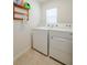 Functional laundry room with a washer, dryer, and storage shelf with cleaning supplies at 682 Olive Conch St, Ruskin, FL 33570