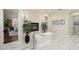 A bright primary bathroom with a soaking tub, white marble floors, a fireplace, and view into the main bedroom at 801 Brightwaters Ne Blvd, St Petersburg, FL 33704