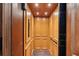Interior view of the wood paneled elevator with carpet flooring and hand rail at 801 Brightwaters Ne Blvd, St Petersburg, FL 33704