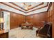 Office with wood paneled walls, tray ceiling, ceiling fan, desk, and upholstered chair at 801 Brightwaters Ne Blvd, St Petersburg, FL 33704