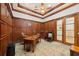 Office featuring wood paneled walls, coffered ceiling, ceiling fan, desk, and wood framed glass door at 801 Brightwaters Ne Blvd, St Petersburg, FL 33704