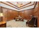 Office with wood paneled walls, tray ceiling, ceiling fan, desk, and upholstered chair at 801 Brightwaters Ne Blvd, St Petersburg, FL 33704