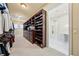 A large walk-in closet with dark wood built-in shelving and a view into the bathroom with marble floors at 801 Brightwaters Ne Blvd, St Petersburg, FL 33704