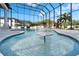 Resort-style pool featuring a table in the water, surrounding sun deck, and palm tree views through the screened enclosure at 9401 93Rd St, Seminole, FL 33777