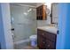 Bathroom featuring a shower-tub combo with sliding glass doors, vanity storage, and a mounted mirror at 1433 Pine Glen Pl # G2, Tarpon Springs, FL 34688