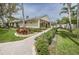 Well-manicured landscaping leading to the community clubhouse with a pool in the background at 1433 Pine Glen Pl # G2, Tarpon Springs, FL 34688