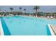 Large community pool featuring lounge chairs, tables with umbrellas, and palm trees at 1433 Pine Glen Pl # G2, Tarpon Springs, FL 34688