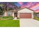Charming one-story home featuring a well-manicured lawn, lush landscaping, and a two-car garage at 15571 Stone House Dr, Brooksville, FL 34604