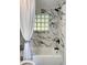 Bathtub featuring modern fixtures and marble-look tiling with a glass block window at 20 Cypress Dr, Palm Harbor, FL 34684