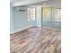Bright living room featuring modern wood-look flooring, large windows, and sliding glass doors to an enclosed porch at 20 Cypress Dr, Palm Harbor, FL 34684