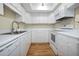 Bright kitchen with white cabinets and appliances, laminate countertops and wood-look floors at 420 64Th Ave # 1005, St Pete Beach, FL 33706