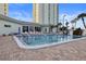 Community swimming pool with lounge chairs, umbrellas, and tropical plants at 420 64Th Ave # 1005, St Pete Beach, FL 33706