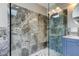 Close-up of luxurious glass-enclosed shower with gray marble tiling and modern fixtures at 4728 Swallowtail Dr, New Port Richey, FL 34653