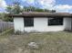 Exterior view of a single-story home showing the yard and boarded up windows at 12812 1St Isle, Hudson, FL 34667
