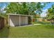 Spacious backyard featuring a shed, green lawn, mature trees, and a paver path at 12918 Cambridge Ave, Tampa, FL 33624