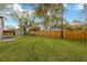 Spacious backyard featuring a lush lawn, a wooden fence, and mature trees at 12918 Cambridge Ave, Tampa, FL 33624