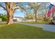 Spacious front yard with mature trees and a long driveway, complemented by an American flag at 12918 Cambridge Ave, Tampa, FL 33624