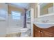 Bathroom featuring white tile, shower-tub, a window, purple shower curtain, vanity and built-in shelving at 1311 Chesterfield Dr, Clearwater, FL 33756