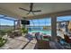 This screened patio features a ceiling fan, outdoor seating, and a lovely view of the lake and sparkling pool at 3091 King Fern Dr, Wimauma, FL 33598