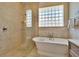 Shower and soaking tub in bathroom with glass block window and neutral color palette at 3110 Bent Creek Dr, Valrico, FL 33596