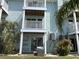 Multi-story condo building featuring private balconies, ground floor patio, and lush tropical landscaping at 657 Garland Cir, Indian Rocks Beach, FL 33785