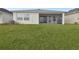 An exterior view of a home's backyard, featuring a screened-in lanai and well-maintained lawn at 11341 Hardwood Hammock Ln, Riverview, FL 33569