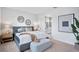 This bedroom features two decorative circular mirrors, a large bed, an ottoman, and an attached bathroom at 11341 Hardwood Hammock Ln, Riverview, FL 33569