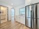 Bright kitchen with stainless steel refrigerator, light wood floors, white cabinets, and view into adjoining bath and bedroom at 2427 10Th S Ave, St Petersburg, FL 33712