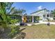 Charming green house featuring vibrant tropical landscaping and a cheerful yellow door with sitting area for guests at 263 42Nd Ne Ave, St Petersburg, FL 33703