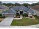Inviting single-story home featuring a well-manicured lawn and a symmetrical facade with arched entryway at 5206 Whispering Leaf Trl, Valrico, FL 33596