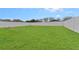 Spacious, manicured backyard with green grass, white fencing, and a fire pit at 5809 War Admiral Dr, Wesley Chapel, FL 33544