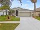 Charming single-story home with manicured lawn, mature palm trees, and a two-car garage at 5809 War Admiral Dr, Wesley Chapel, FL 33544