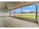 Enclosed patio with ceiling fan and view of spacious backyard with fire pit and white fencing at 5809 War Admiral Dr, Wesley Chapel, FL 33544