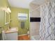 Well-lit bathroom with a single sink vanity, a ceramic-tiled shower, and a patterned shower curtain at 1309 Nokomis S Ave, Venice, FL 34285