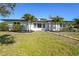 Charming single-story home featuring a lush green lawn and tropical palm trees in the front yard at 1309 Nokomis S Ave, Venice, FL 34285