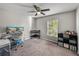 Well-lit bedroom with functional desk area, neutral carpeting, and a stylish ceiling fan at 10511 Fuzzy Cattail St, Riverview, FL 33578