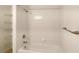 Bright bathroom featuring a bathtub with white tile surround, shower, and convenient shelving at 1275 Drew St, Clearwater, FL 33755
