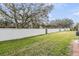 Fenced backyard with green lawn and mature trees at 1308 Costa Mesa Dr, Wesley Chapel, FL 33543