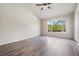 Bright bedroom features wood-look flooring, ceiling fan, and large window with exterior views at 1308 Costa Mesa Dr, Wesley Chapel, FL 33543