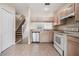 Kitchen featuring white appliances, tile flooring, a dishwasher, and stairs to the left at 1308 Costa Mesa Dr, Wesley Chapel, FL 33543