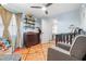 Bedroom with wood-look floors, ceiling fan, dresser changing table, crib, and a gray chair at 13215 Parkhurst Ct, Riverview, FL 33569