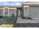 Close-up of front entrance with gray siding, neatly kept landscape, and a storm door at 13215 Parkhurst Ct, Riverview, FL 33569