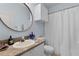 Well-lit bathroom with a round mirror, vanity, and shower with curtain at 2765 Via Cipriani # 1232B, Clearwater, FL 33764