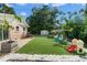 Backyard featuring artificial turf, a patio, picnic table, playground, and white gravel borders at 651 Southwest N Blvd, St Petersburg, FL 33703