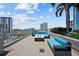 Relaxing rooftop deck with modern blue couches, fire pit, and stunning city views under a blue sky at 777 N Ashley Dr # 2503, Tampa, FL 33602
