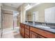 Bathroom with a double sink vanity, granite countertops, framed mirrors and a stand-up shower with glass door at 12537 Silverdale St, Tampa, FL 33626