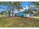Charming blue single story home with a well-maintained front yard, mature trees, and a driveway leading to the garage at 13851 102Nd Ave, Largo, FL 33774
