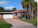 Inviting single-story home with a brick driveway and tropical palm trees at 15806 Redington Dr, Redington Beach, FL 33708